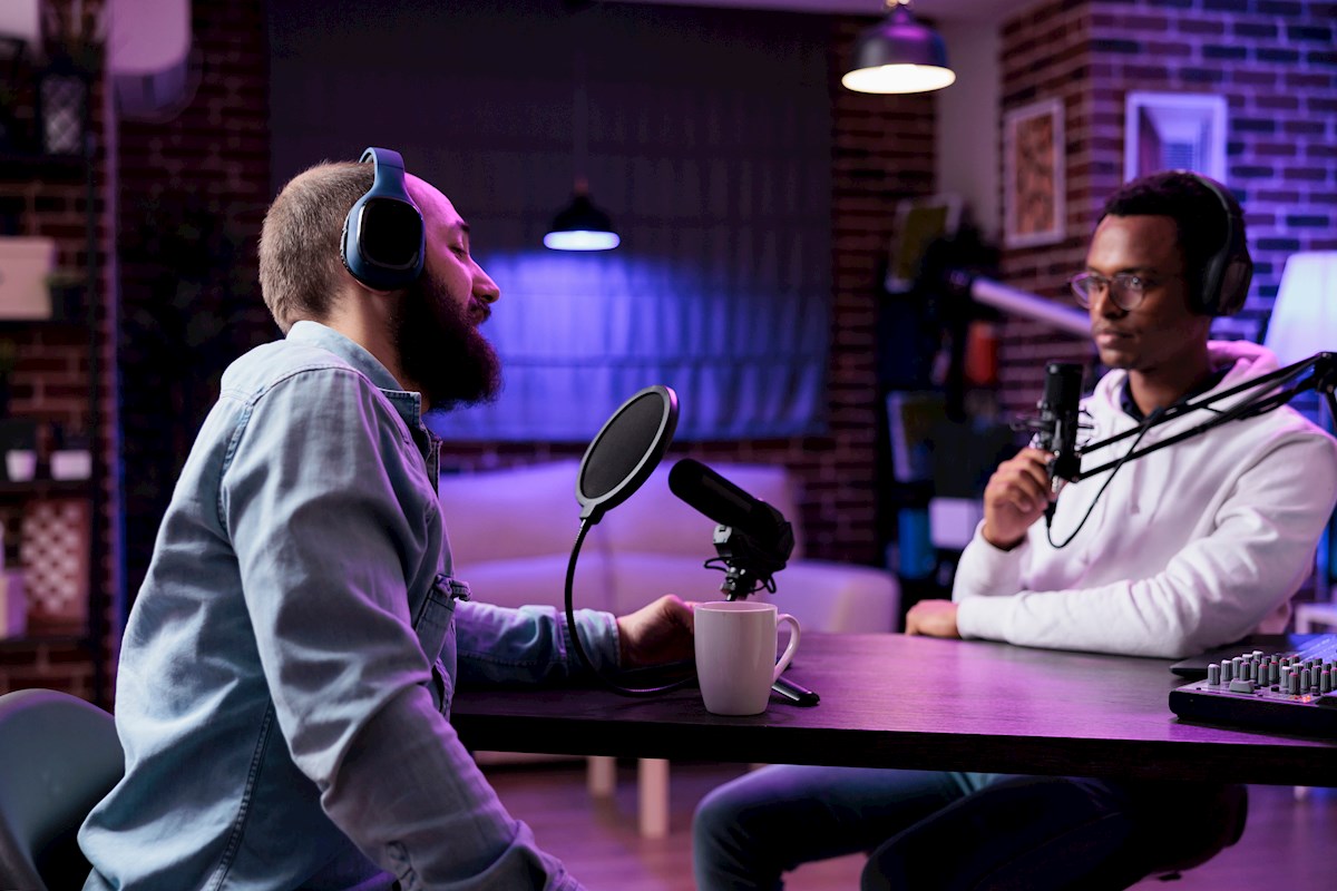 Two men talking in an interview with microphones and headphones